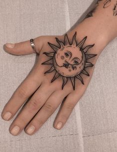 a hand with a sun and moon tattoo on it