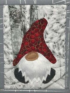 an image of a gnome face on a quilted wall hanging ornament with red and white trim