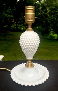 a white glass lamp sitting on top of a table next to a green grass covered field