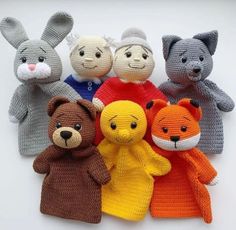 knitted stuffed animals are arranged in a row on a white surface with one bear, the other fox, and two bears