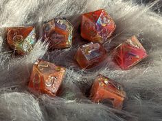 several red and gold dice sitting on top of white fur covered surface with silver flecks