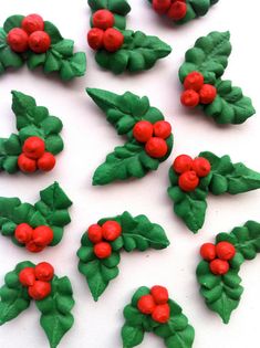 some red and green decorations are on a white surface with holly leaves in the middle