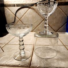 two glass goblets sitting on top of a counter