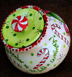 a ceramic bowl with candy canes on it and the lid is decorated in green