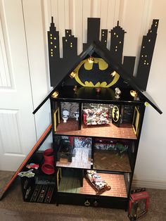 a toy house with batman decorations on the top and bottom floor, in front of a white door