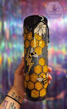 a hand holding a can with bees and honeycombs on it