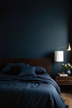 a bedroom with dark blue walls and wooden bed frame, white lamps on nightstands