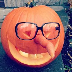 a close up of a pumpkin with glasses on it's face and tongue sticking out