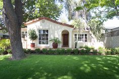 a small white house sitting in the middle of a lush green yard next to a tree