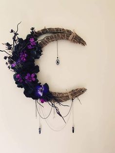 a clock made out of branches with flowers on the front and side, hanging from it's sides