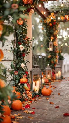 an outdoor area with pumpkins and greenery on the ground, candles in front of them