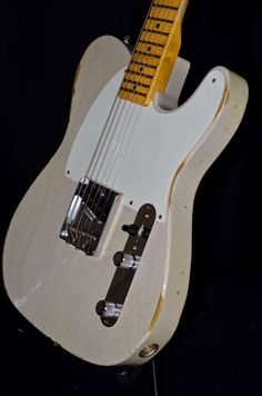 an electric guitar is sitting on display in a black background with the strings still attached to it