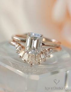 an emerald cut diamond ring on top of a clear box