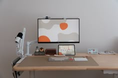 a computer monitor sitting on top of a wooden desk next to a lamp and cell phone