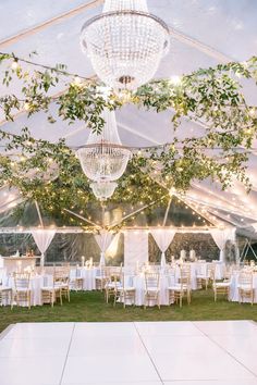 the inside of a tent with tables, chairs and chandelier