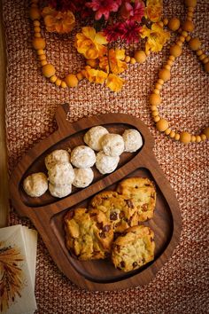 cookies and biscuits on a wooden tray with flowers in the backgrouf area