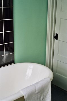 a white bath tub sitting next to a green wall