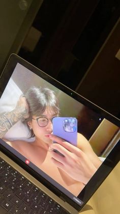 a laptop computer sitting on top of a desk with a woman's face on the screen