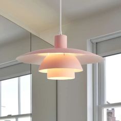 a light fixture hanging from the ceiling in a room with large windows and white walls