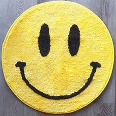 a yellow smiley face rug sitting on top of a wooden floor