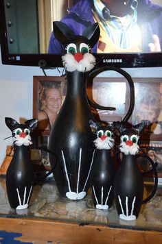 a group of black cat figurines sitting on top of a table next to a tv