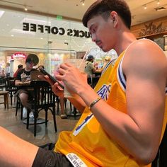 a young man sitting in front of a table using a cell phone and looking at his watch