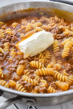 a large pot filled with pasta and sauce on top of a stove next to a spatula