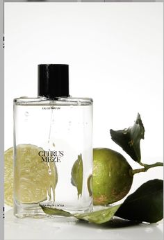 a bottle of perfume sitting next to two limes