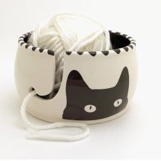 a black and white cat design bowl with yarn in it's mouth, on a white background