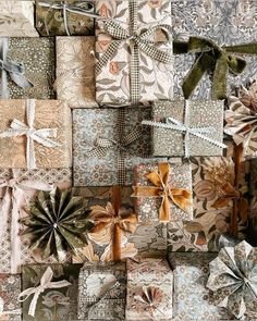 many wrapped presents are stacked on top of each other, with ribbons and bows around them