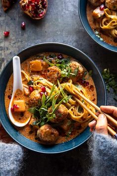 someone holding chopsticks over a bowl of noodles with meatballs and veggies