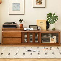 a record player sitting on top of a wooden cabinet next to a potted plant