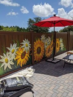 a patio with sunflowers painted on the fence and an umbrella in the middle