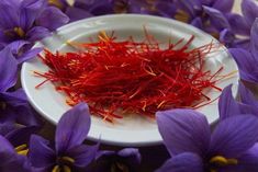 a white plate topped with purple flowers and saffroni petals on top of a table