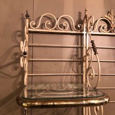 an old metal shelf with glass shelves on the top and bottom, sitting against a wall