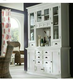 a white china cabinet with glass doors and drawers in a living room area next to a window