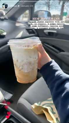 someone is holding up a starbucks drink in their car