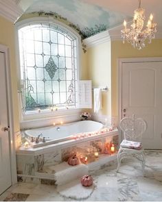 a bathtub with candles on the floor and a chandelier hanging above it