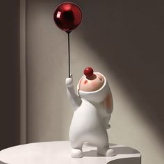 a white bear holding a red balloon on top of a table