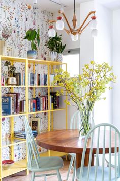 a dining room table and chairs with bookshelves in the backround behind them