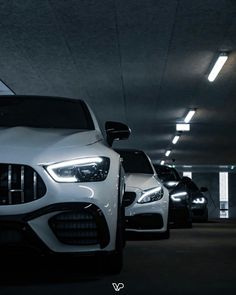 several cars are parked in a parking garage with lights on and one car is white