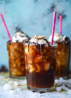 two glasses filled with ice cream and chocolate syrup on top of snow covered ground next to each other