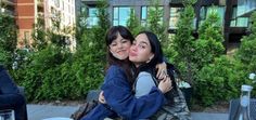 two women hugging each other at an outdoor table