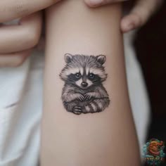 a small raccoon tattoo on the arm