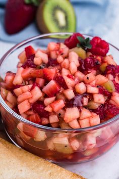 a glass bowl filled with fruit salad on top of a white plate next to crackers