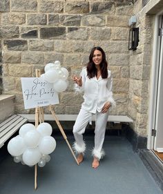 a woman standing next to a sign and balloons