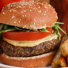 a hamburger with lettuce, tomato and cheese next to french fries on a plate