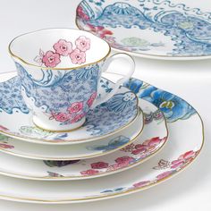 two tea cups and saucers with floral designs on them, one is blue and the other has pink flowers