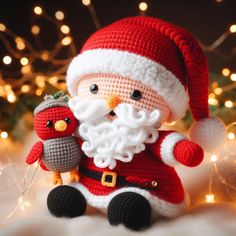 a crocheted santa clause holding an owl in front of a christmas tree with lights