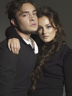 a young man and woman are posing for a photo in front of a dark background